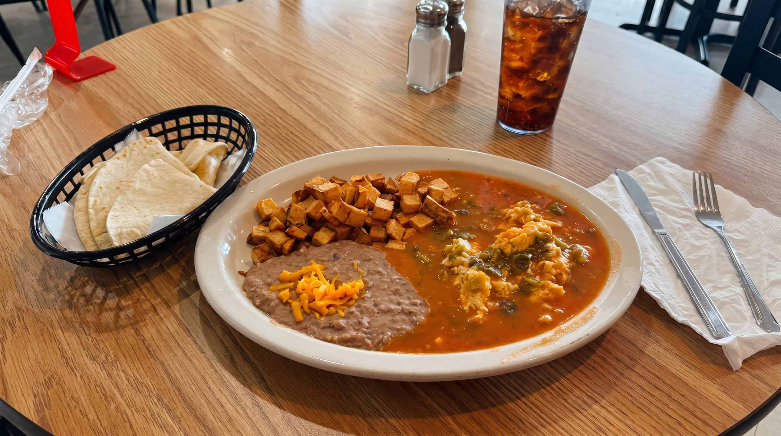 Mexican breakfast plate with eggs, beans, potatoes, and tortillas