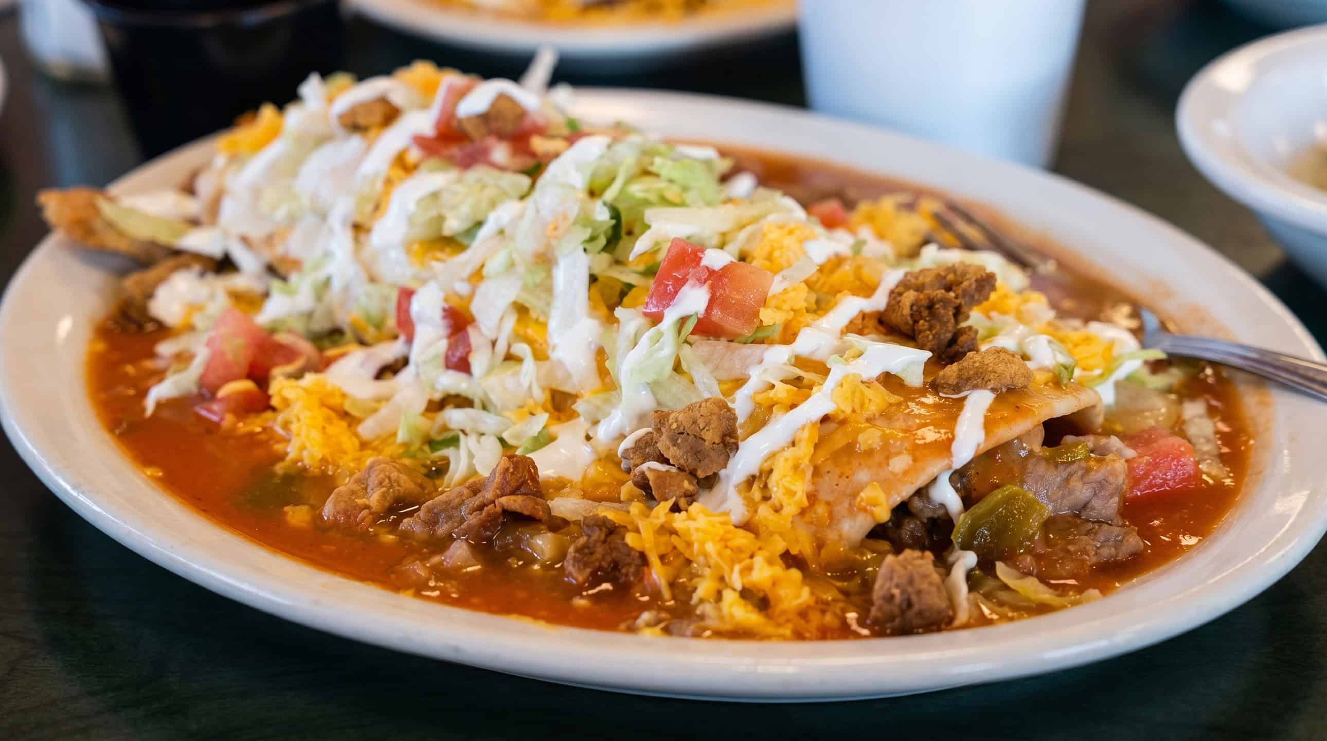 A plate of smothered Mexican comfort food covered in hot green chili at Alberto's Express in Greeley, CO